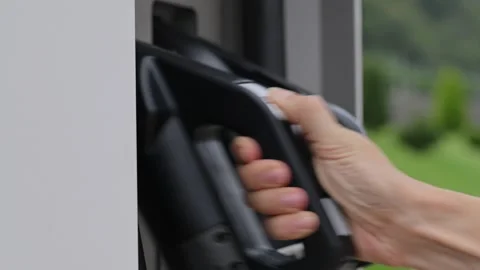 Close-up of young woman's hand taking charging port of electric car at public Stock Footage 212024796