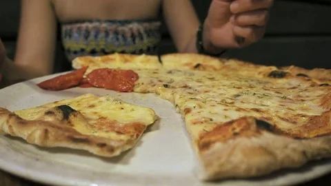 Close up of young woman's hands eating pizza in the restaurant Stock Footage 79386164