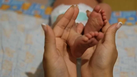 Close-up of a young woman's hands holding her baby's legs. Stock Footage 119769582