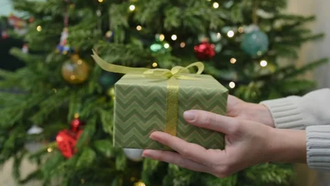 Close-up of young woman's hands holding New Year's gift box with golden ribbon Stockbeeldmateriaal 219336341