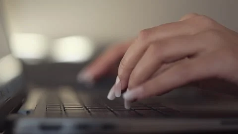 Close up of young woman's hands with long nails typing on a laptop keyboard Stock Footage 296099873