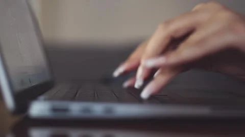 Close up of young woman's hands with long nails typing on a laptop keyboard Stock Footage 296100281