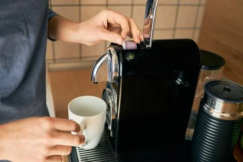 Close-up of a young woman's hands making espresso in an espresso capsule machine Stock Photos