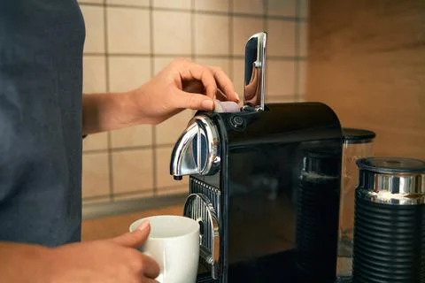 Close-up of a young woman's hands making espresso in an espresso capsule machine Stock Photos