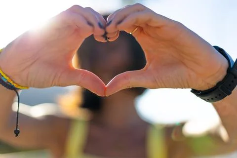Close-up of young woman's hands making heart shape with fingers. Portrait o.. Stock Photos