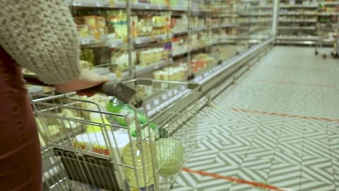 Close-up of a young woman's hands moving a grocery cart through the aisles of a Stock Footage 196793620