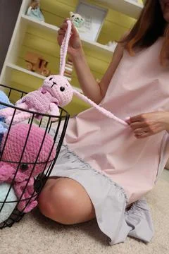 Close-up of a young woman's hands pulling a naughty pink hare from a basket by Stock Photos