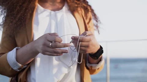 Close-up of young woman's hands untangling tangled earphones Stock Footage 131567290