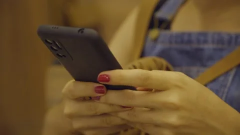 Close-up of a young woman's hands using a cell phone, scrolling Vídeo Stock 323231769