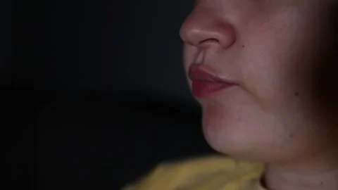 Close up of a young woman's lips as she eats popcorn while watching a movie. 库存影片 336900503