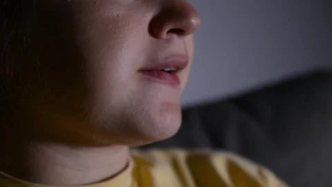 Close up of a young woman's lips as she eats popcorn while watching a movie. Video stock 336900505