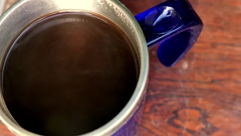 Close-up (zoom in) of a thermal coffee cup on a table. Steam rises intensely Stock Footage 344512138