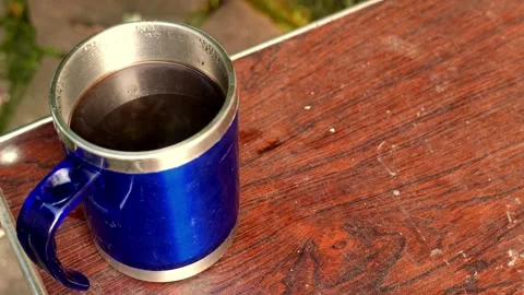 Close-up (zoom in): thermal coffee cup on a table. Steam rises from an espresso Stock Footage 345099643