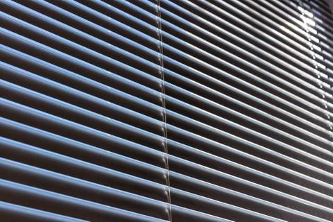 Closed aluminium roller blinds pattern and texture. Blue sky and rays of ligh Stock Photos