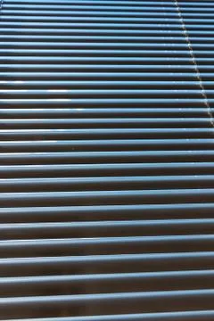 Closed aluminium roller blinds pattern and texture. Blue sky and rays of ligh Stock Photos