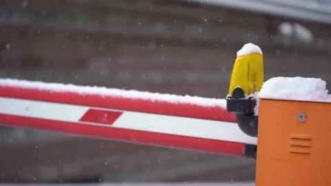 Closed barrier on the road. White-red striped gate, yellow signal light. Winter. 動画素材 169660608