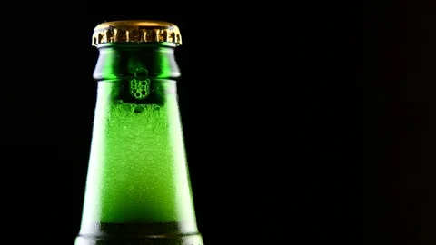 A closed beer bottle rotates on a black background. Stock Footage 126311041