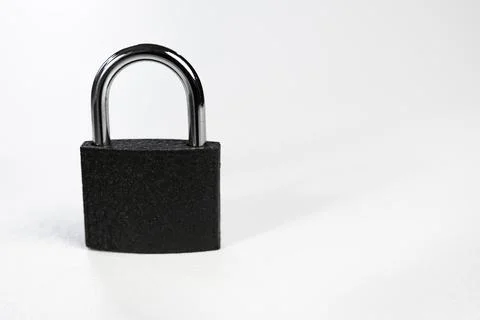 Closed black padlock with chrome shackle isolated on light background Stock Photos