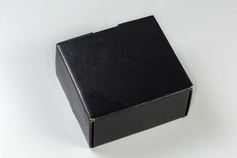 Closed black rectangular cardboard packing box on a gray background Stockfoto's