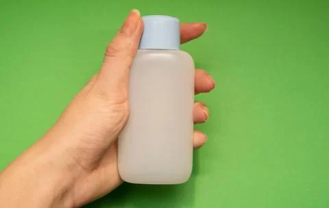 A closed Blue can of detergent liquid in the left female hand in the centre o Stock Photos