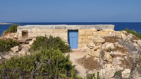 A closed blue door in a stone wall in front of sea Stock Footage 108387561