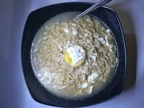 Closed up boiled noodle with egg on top in black bowl Stockfoto's