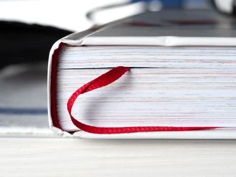 Closed book with a bookmark in the form of a red ribbon close-up. The book is Stock Photos