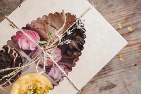 Closed box with different cakes wrapped with thread, on a wooden background. Stock Photos