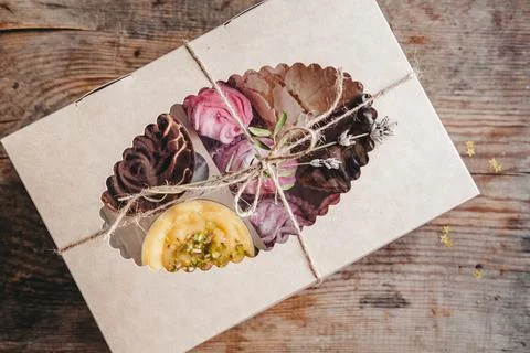 Closed box with different cakes wrapped with thread, on a wooden background. Stock Photos