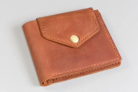 Closed buttoned classic brown leather wallet on a gray background Stock Photos