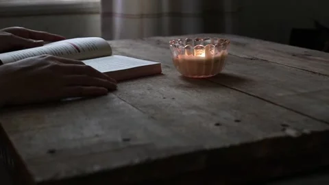 Closed up of a candle lights the book being read Stock Footage 295787849