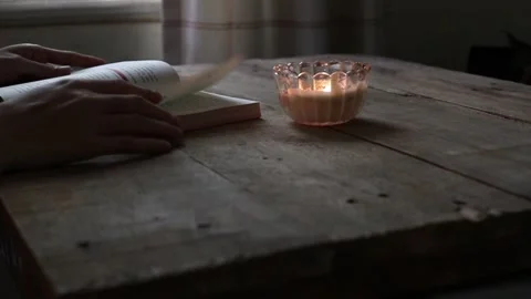 Closed up of a candle lights the book being read Stock Footage 295787851