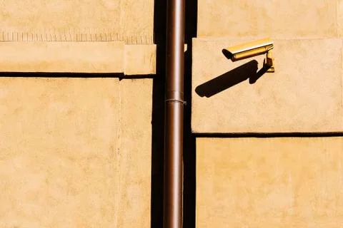 Closed circuit television (CCTV) camera on a yellow building wall. Stock Photos