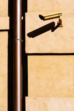 Closed circuit television (CCTV) camera on a yellow building wall. Stock Photos