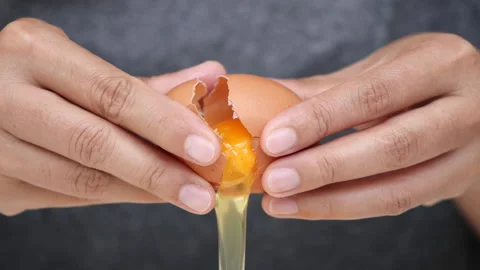 Closed up cracking fresh chicken egg, slow motion woman hands breaking an egg. Vídeo Stock 142692756