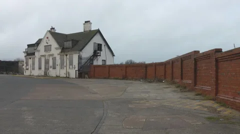 Closed down pub with metal shuttered windows red brick wall of old ship yard. Stock Footage 1090710