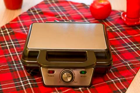 Closed Electronic waffle-iron. View of the kitchen with a beautiful red backg Stock Photos