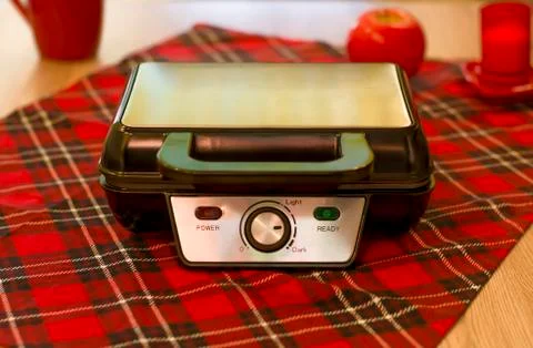 Closed Electronic waffle-iron. View of the kitchen with a beautiful red backg Stock Photos