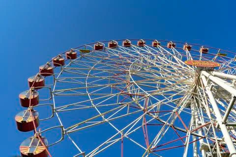 Closed, empty, non-working attraction Ferris wheel with empty booths against Stock Photos