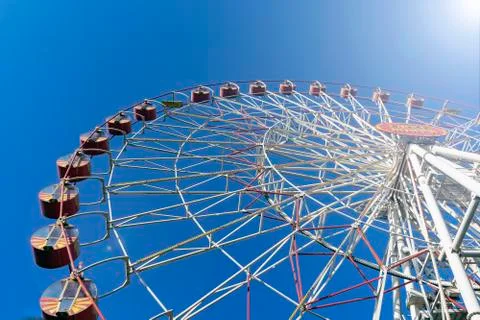 Closed, empty, non-working attraction Ferris wheel with empty booths against Stock Photos
