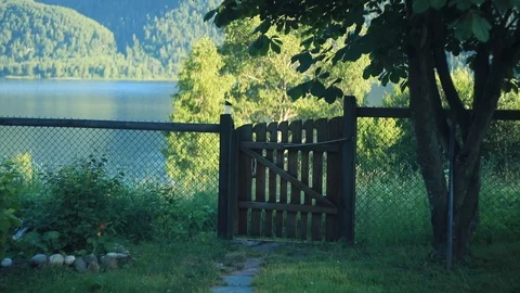 Closed garden gate with a view of a mountain lake shot in summer Stock Footage 105947077