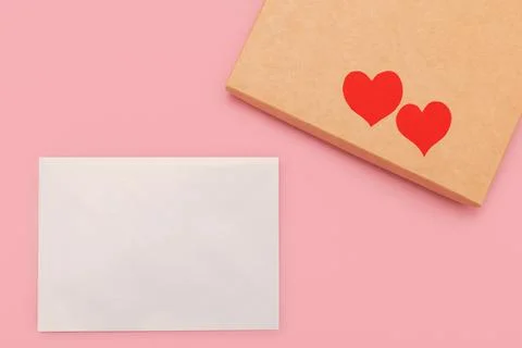 Closed gift box and two paper hearts on it isolated on pink background Stock Photos