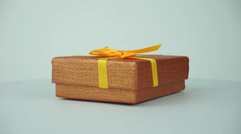 Closed gift box with golden bow. Rotating 360 degrees on empty background. Stock Footage 41813084