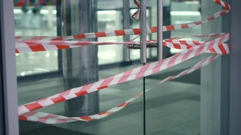Closed glass door to the mall with a pull-out barrier tape. Closed entrance 動画素材 120536160