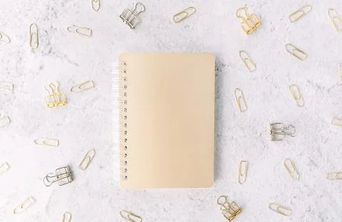 Closed gold notepad on background with set of silver and gold paper clips on Stock Photos