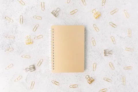 Closed gold notepad on background with set of silver and gold paper clips on Stock Photos