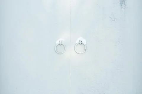 A closed gray gate with round handles sprinkled with snow. Stock Photos
