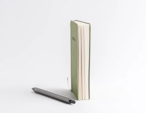 Closed green notebook standing vertically with a pen lying beside it isolat.. Stock Photos