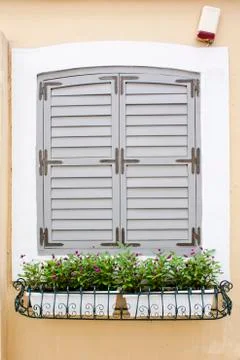 The closed grey window on the yellow wall Фото
