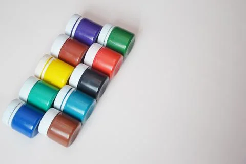 Closed jars of colored gouache, lying in a row on a light background. Multi-c Stock Photos